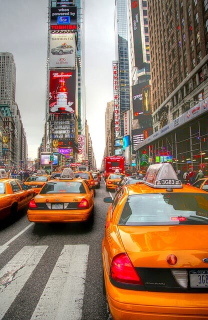 new york road with filled taxis and red double decker tour buses