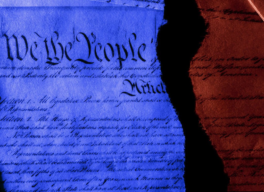 The United States Constitution in red and blue torn in half representing division between Democrats and Republicans
