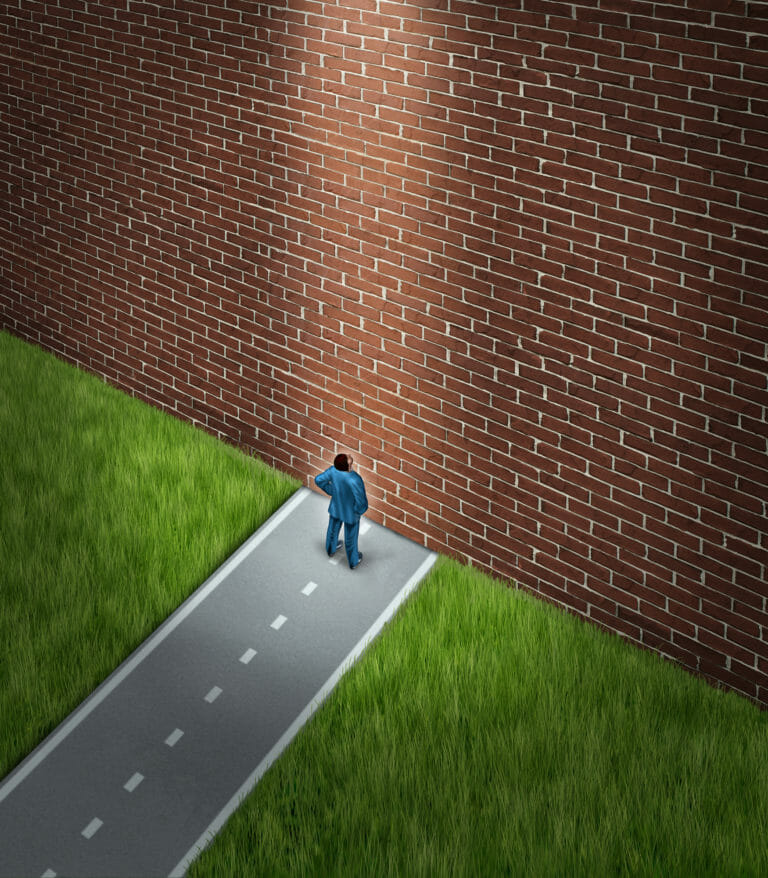 Man standing on road blocked by brick wall