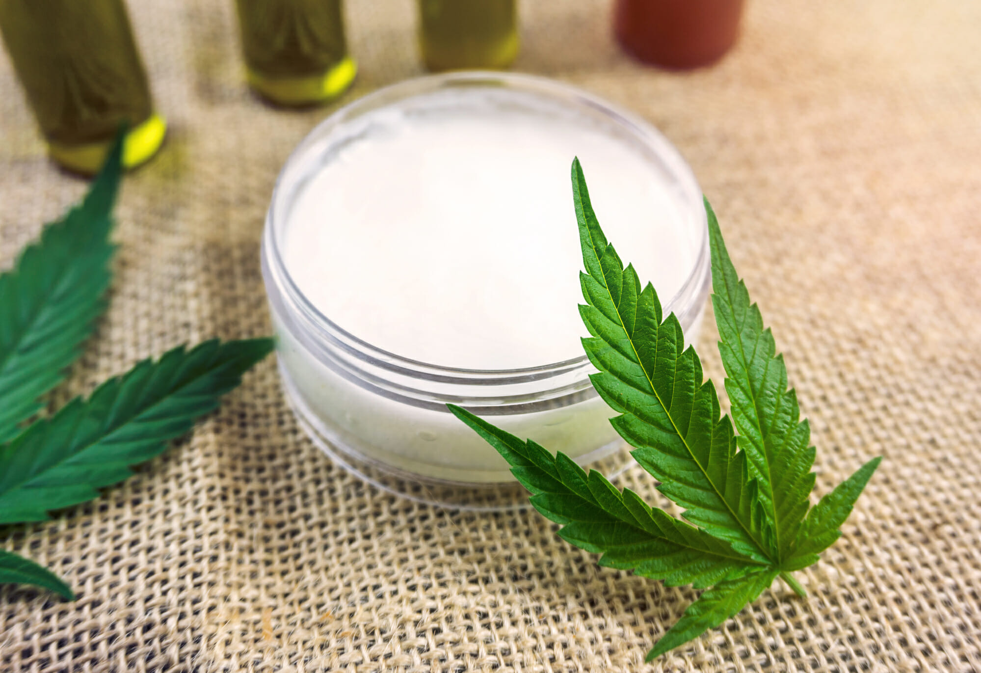 Cannabis CBD gel in jar with cannabis leaf on hemp cloth burlap