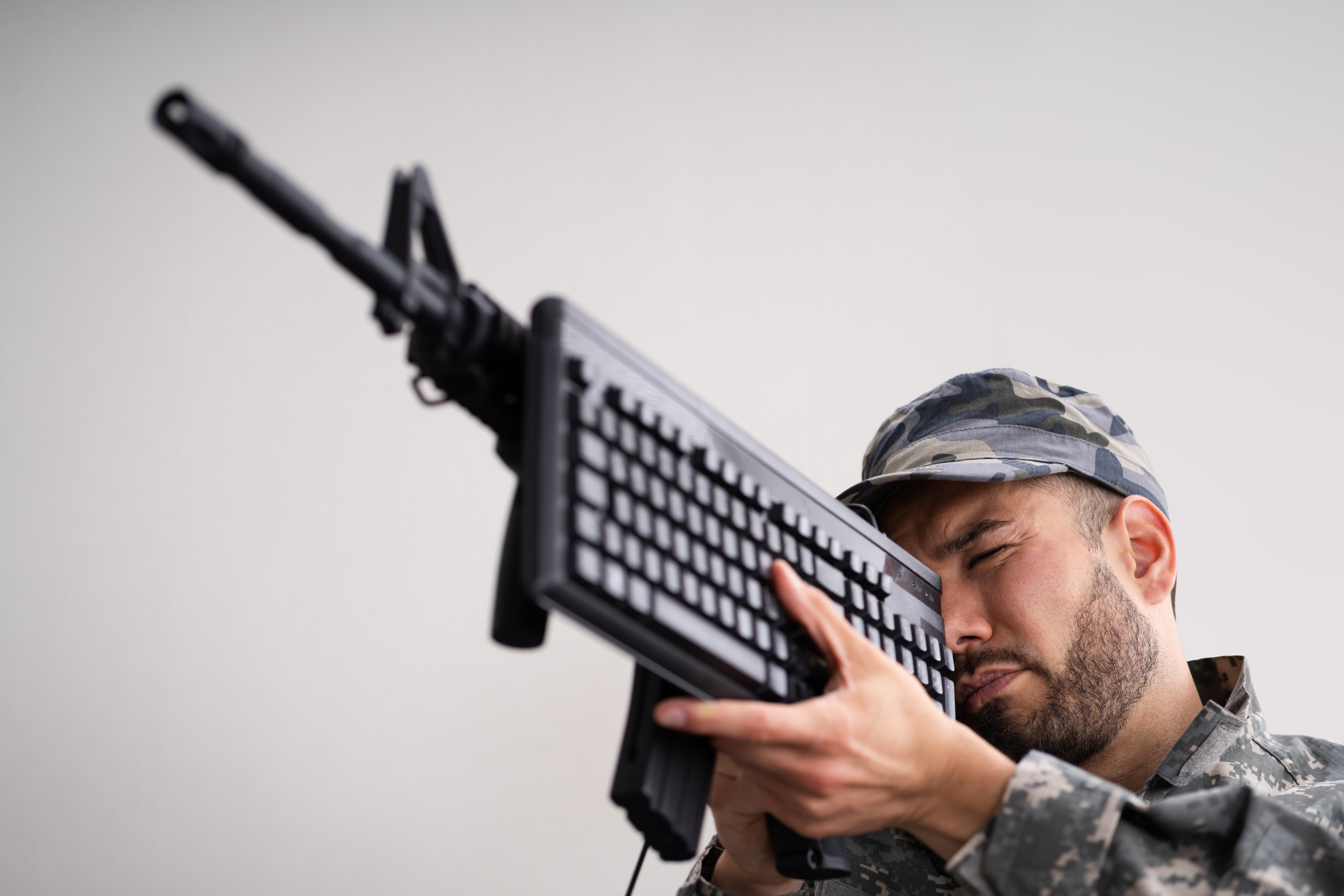 man in military uniform holding up gun with keyboard next to it