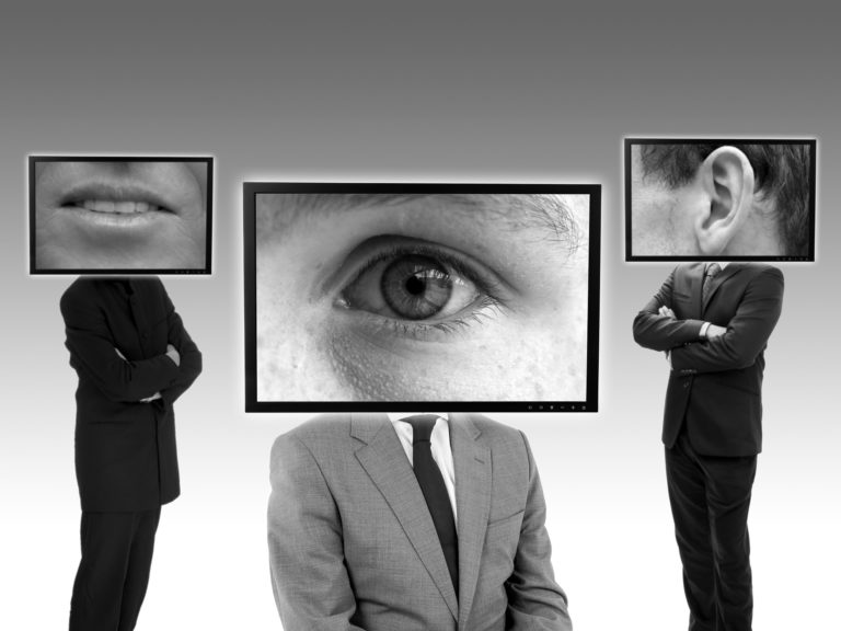 men in suit with computer screens as heads with images of eyes, ears, and mouths